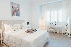 a white bedroom with a white bed and a desk at Vv CONDEVEGA in Telde