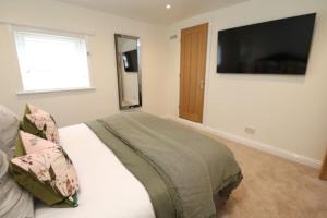 a bedroom with a bed with a television on the wall at The Cottage IH3ATL in Stockton-on-Tees