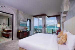 a bedroom with a large bed and a view of the ocean at Patong Signature Boutique Hotel in Patong Beach