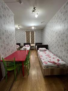 a room with two beds and a table and chairs at Iso Hostel in Tashkent