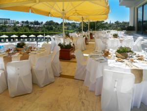 Dekelia Hotel في أثينا: مجموعة طاولات مع كراسي بيضاء ومظلات