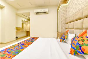 a bedroom with a large white bed with colorful pillows at FabHotel Hill Park in Ahmedabad