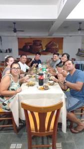 a group of people sitting around a table eating at condominio colonial pousada mariscal in Canto Grande
