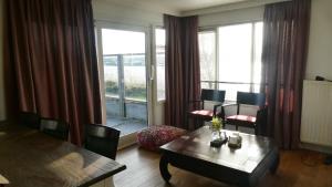 Una sala de estar con una mesa y sillas y una gran ventana. en Havenzicht, en Oostmahorn