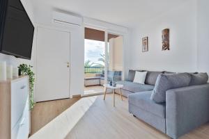 ein Wohnzimmer mit einem Sofa und einem TV in der Unterkunft Apartamento ESTRELLA con vistas a la piscina in Torrevieja