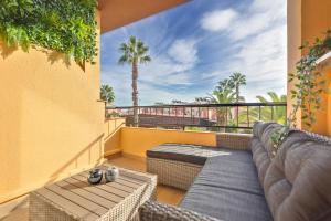 einen Balkon mit einem Sofa und Blick auf Palmen in der Unterkunft Apartamento ESTRELLA con vistas a la piscina in Torrevieja