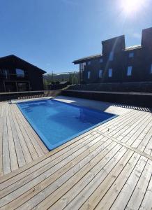 una gran piscina azul en una terraza de madera en Fjällnära Skilodge 19, en Sälen
