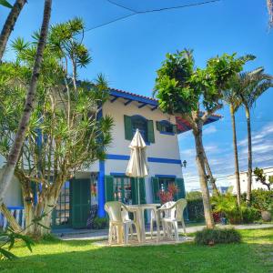 a house with a table and chairs and palm trees at condominio colonial pousada mariscal in Canto Grande