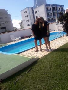 two women are standing next to a swimming pool at condominio colonial pousada mariscal in Canto Grande