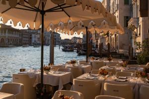 a restaurant on the water with tables and chairs at The Venice Venice Hotel in Venice