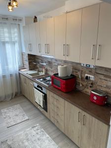 uma cozinha com armários brancos e um micro-ondas vermelho em Mary's Apartment em Suceava