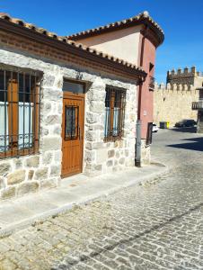 a stone building with a wooden door on a street at Casas del Castillo, 4 in Ávila