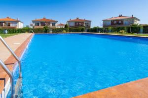 a large blue swimming pool with houses in the background at Rentalmar Montroig Natura in Miami Platja