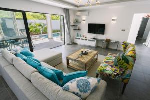un soggiorno con divano, sedie e TV di Pearl Collection a Grand Baie