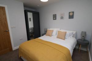 a bedroom with a large bed with a yellow blanket at The Hive - IH21ALL - APT 2 in Thornaby on Tees