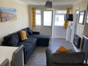 a living room with a blue couch and chairs at MaterMolly Hemsby Chalet Hire 240 Belle aire beach road Hemsby NR29 4HZ in Hemsby