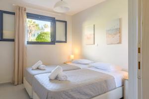 two beds in a white room with a window at Golden Aura in Danilia +44 photos