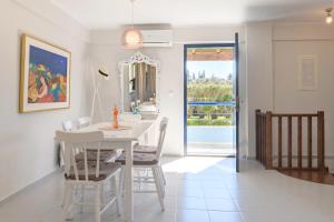a white dining room with a white table and chairs at Golden Aura in Danilia