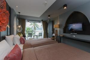 ein Hotelzimmer mit zwei Betten und einem Flachbildfernseher in der Unterkunft Patong Signature Boutique Hotel in Patong Beach