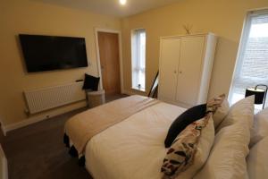 a bedroom with a large bed with a television on the wall at The Loft - IH21ALL - APT 9 in Thornaby on Tees