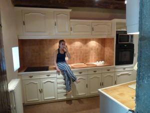 a woman sitting on a kitchen counter talking on a cell phone at Le Gite de la Prunette in Le Grau-dʼAgde