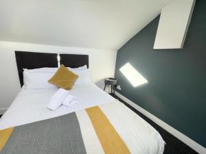 um quarto com uma cama grande e uma almofada amarela em The Central Suite Sasco Apartments em Blackpool