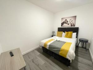 um quarto branco com uma cama e piso em madeira em The Central Suite Sasco Apartments em Blackpool