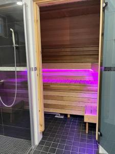 タンペレにあるStunning 5BR 16 Bed Home with Finnish Sauna & Jacuzzi 340 m2のバスルーム(紫色の照明が付くサウナ付)