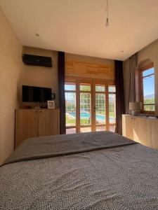 a bedroom with a large bed and a television at Villa, piscine sans vis à vis et hammam privé. in Agadir Toudras