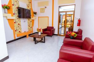 a waiting room with red couches and a tv at Dodoma Shine Lodge in Dodoma