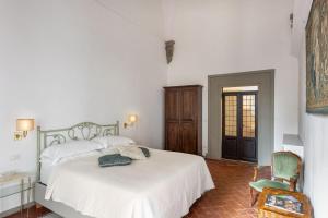 a white bedroom with a bed and a chair at Palazzo Roselli Cecconi Apartments in Florence