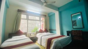 two beds in a blue room with a window at Hotel Discovery Inn in Kathmandu