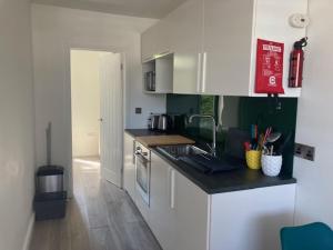 a kitchen with white cabinets and a counter top at The Salt Box- Lovely refurbished annexe, free parking, walk to Porth beach. in Saint Columb Minor