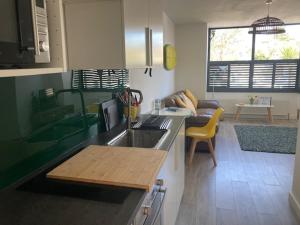 a kitchen with a sink and a living room at The Salt Box- Lovely refurbished annexe, free parking, walk to Porth beach. in Saint Columb Minor