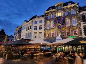 eine Gruppe von Tischen und Sonnenschirmen vor einem Gebäude in der Unterkunft Hotel Pauw in Nijmegen