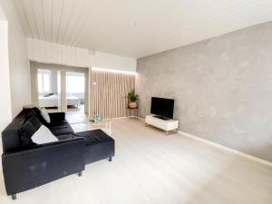 sala de estar con sofá negro y TV en City Style en Jyväskylä