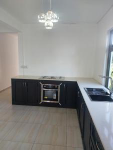 a kitchen with black cabinets and a sink and a stove at The Oasis of Serenity Villa in Grande Rivière Sud Est
