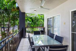 uma varanda com uma mesa de vidro e cadeiras em Zion Escapes Cairns City Waters Edge Family Apartment em Cairns