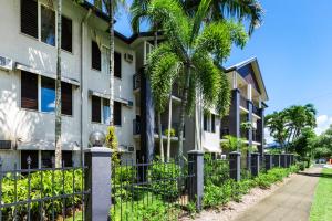 a building with palm trees next to a sidewalk at Zion Escapes Cairns City Waters Edge Family Apartment in Cairns