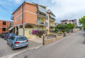 a building with cars parked on the side of a street at Apartment Marigold in Sveti Filip i Jakov