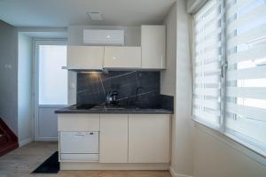 een keuken met witte kasten, een wastafel en een raam bij The Adour - Apartment 42 m in Vic-en-Bigorre