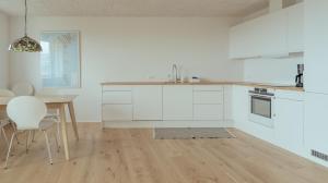 cocina con armarios blancos, mesa y sillas en New 2BR Apartment / Sea View, en Tórshavn