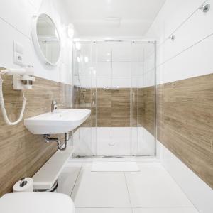 ein Bad mit einer Dusche und einem Waschbecken in der Unterkunft VacationClub - Boulevard Residence Apartament 1 in Ustronie Morskie