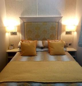 um quarto com uma cama com almofadas amarelas e duas luzes em Glan Hirfaen Where the mountains meet the sea em Porthmadog