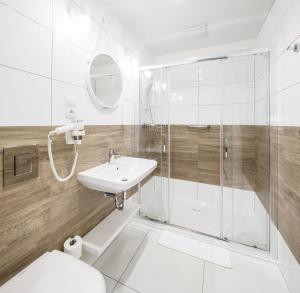 a white bathroom with a shower and a sink at VacationClub - Boulevard Residence Apartament 1 in Ustronie Morskie