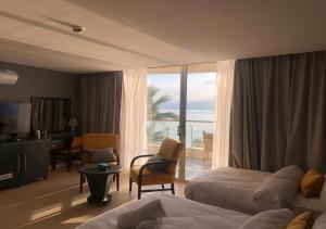 a hotel room with a bedroom with a view of the ocean at O Beach Hotel & Resort in Sowayma