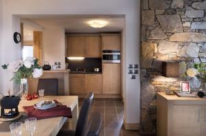 eine Küche und ein Esszimmer mit einer Steinmauer in der Unterkunft CGH Résidences & Spas La Grange aux fées in Valmorel