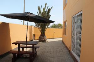 a table and benches with an umbrella in a courtyard at The Timeless Way Self Catering Accommodation in Swakopmund