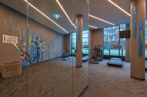 une salle de sport avec des appareils d'exercice et un grand mur de verre dans l'établissement Adina Apartment Hotel Vienna Belvedere, à Vienne