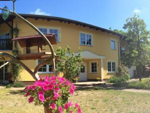 ein gelbes Haus mit rosa Blumen davor in der Unterkunft Ferienwohnung Mühlenblick in Benz